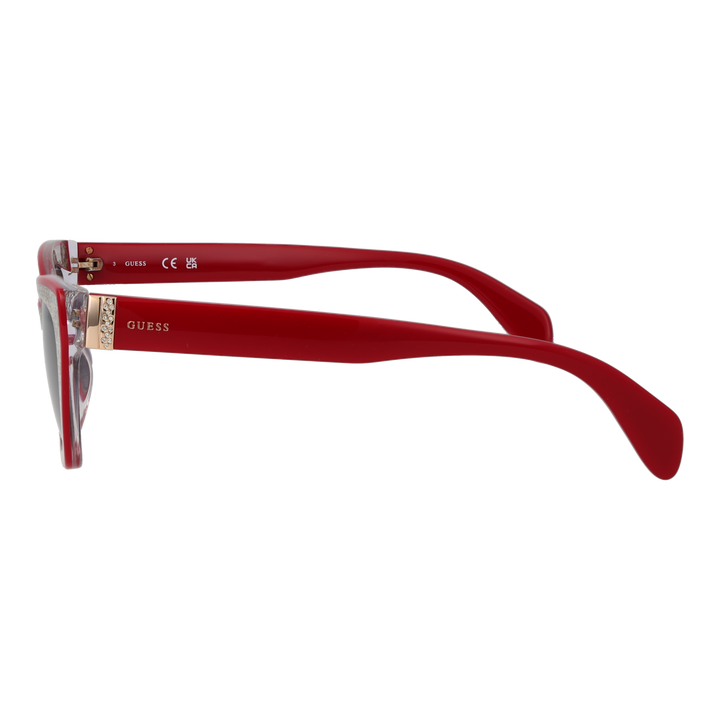 Red and black textured cat-eye sunglasses with gradient grey lenses and decorative gold chain over a neutral background