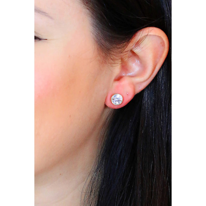 Pair of gold-tone stud earrings with round faceted clear crystals on white background, front view