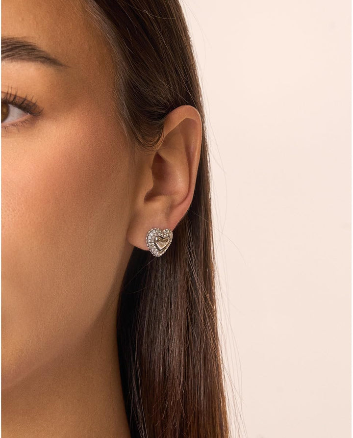Pair of silver heart-shaped stud earrings set with small sparkling crystals on white background